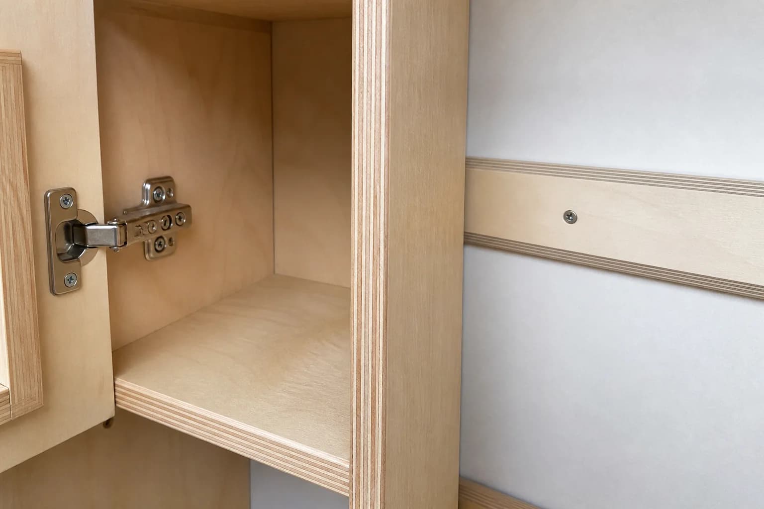 Plywood cabinet and lightweight vehicle panel junction showing layered edges, finish and hinge hardware