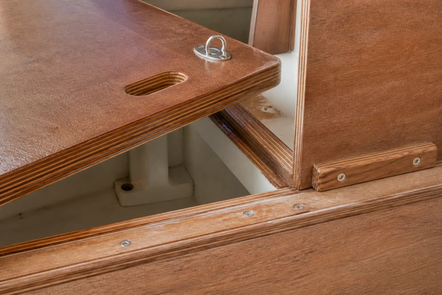Coated marine plywood hatch and cabinet joint with visible sealed layered edges and stainless fasteners