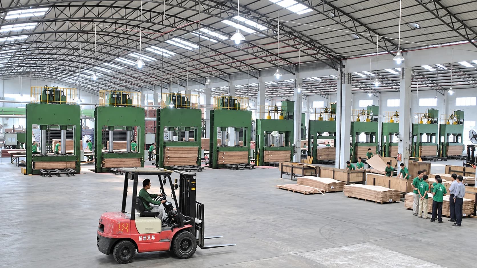 Wide view of a plywood workshop floor in Linyi with press equipment, panel handling and a forklift